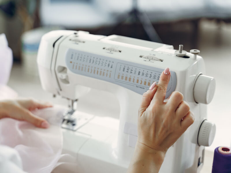 A closeup of a woman using a sewing machine.